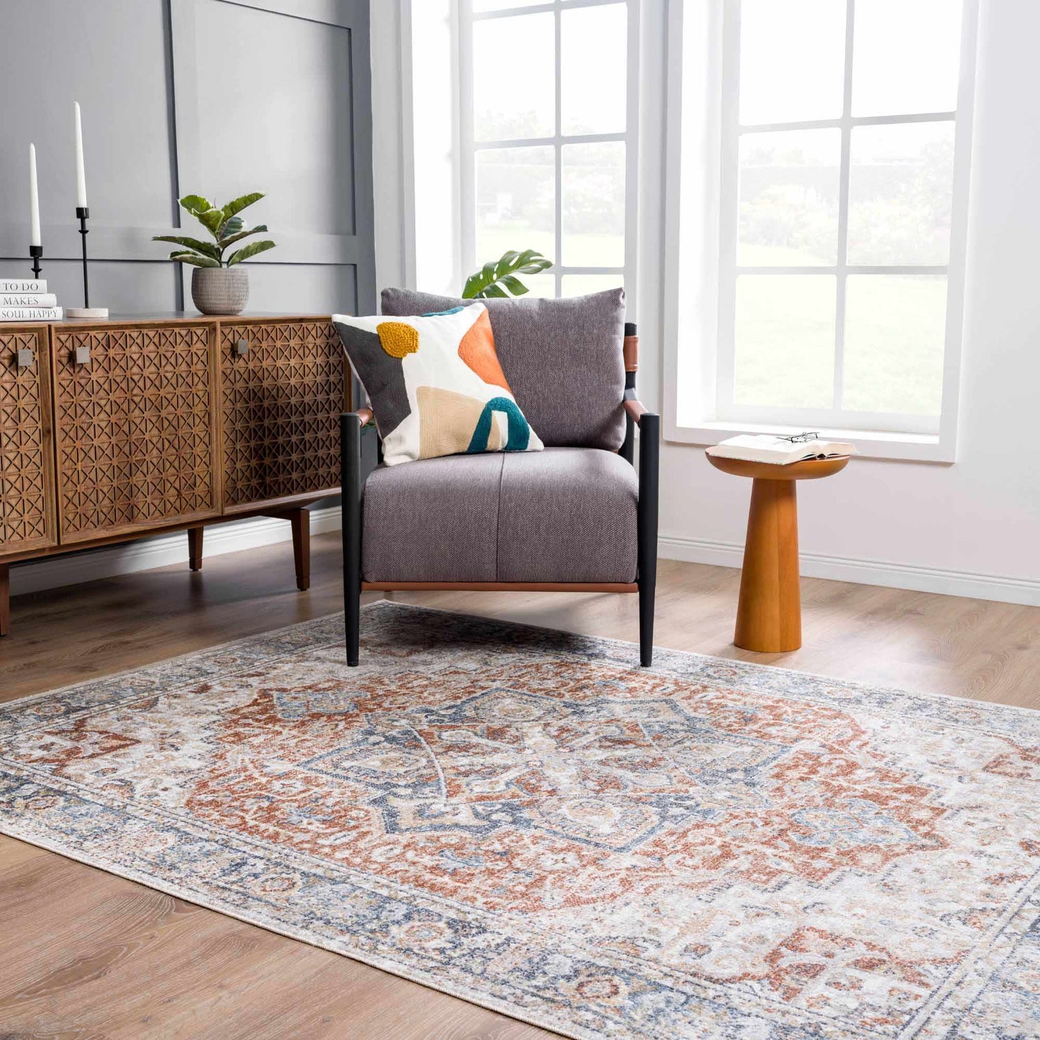 Living room scene with a Neta Red & Blue Flat Pile Washable Rug, gray chair, wood cabinet, and natural light. Roomscene-Rectangle