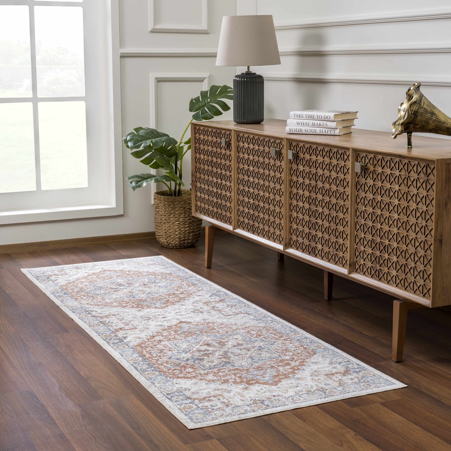Living room scene with a Neta Red & Blue Flat Pile Washable Rug, wood console table, lamp, and monstera plant. Roomscene-Runner