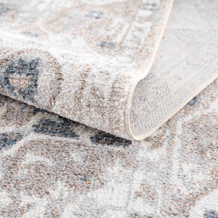 Close up of the Dobry Boutique Washable Rug showing the blue, tan, and off-white oriental pattern and soft, textured material. Fold