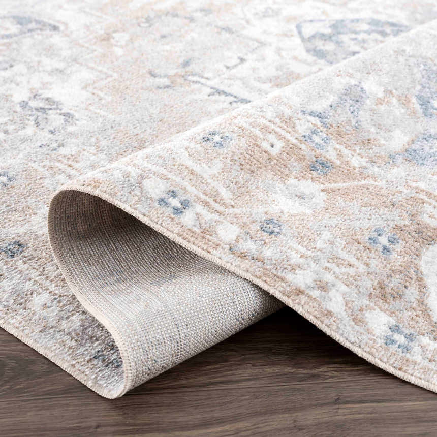 Close-up of the Dobry Boutique Washable Rug showing its blue, off-white, and tan vintage-style pattern and texture. Fold