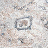 Close-up of the Dobry Boutique Washable Rug. Features a blue, tan, and off-white traditional pattern and soft texture. Texture