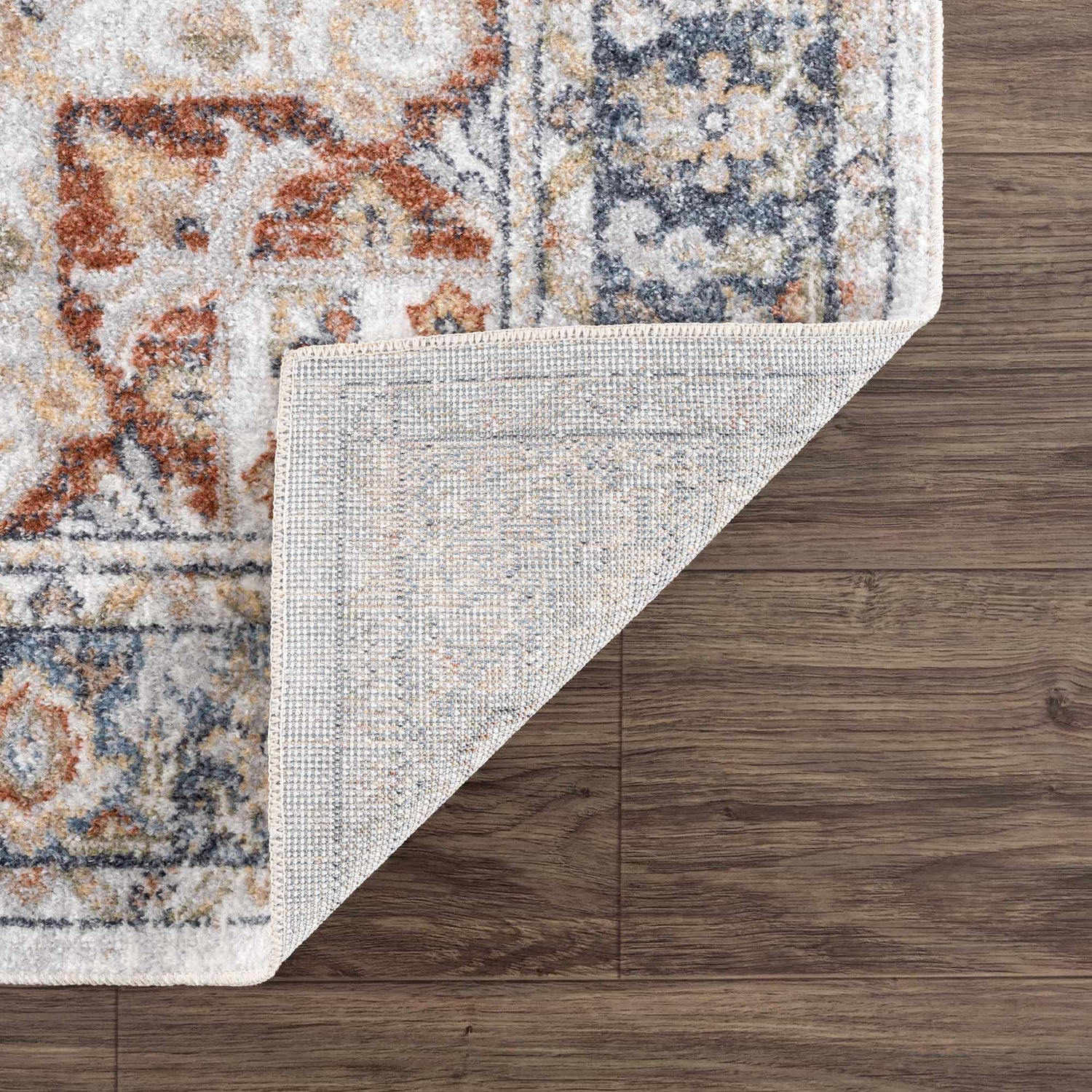 Close-up of Akram Gray & Orange Washable Area Rug showing the traditional vintage pattern and rug backing. Fold