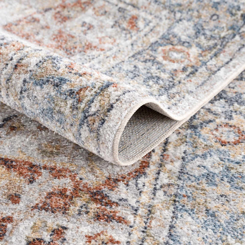 Close-up of the Akram Gray & Orange Washable Area Rug, showing the traditional vintage pattern and soft polyester texture. Fold