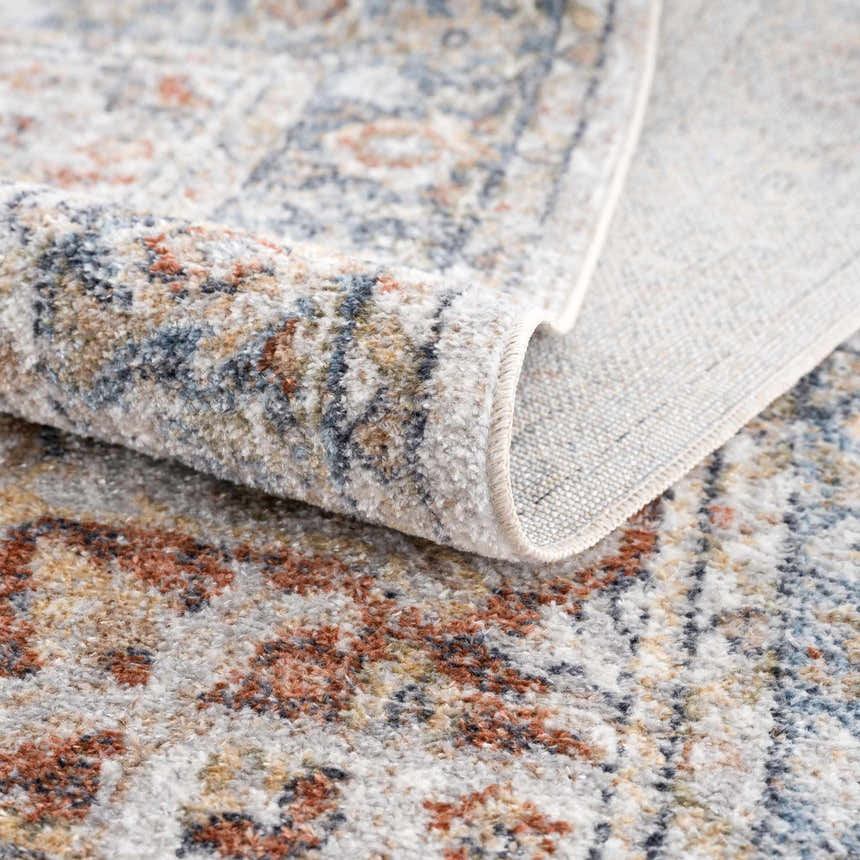 Close-up of the Akram Gray & Orange Washable Area Rug showing its traditional vintage pattern and soft polyester texture. Fold
