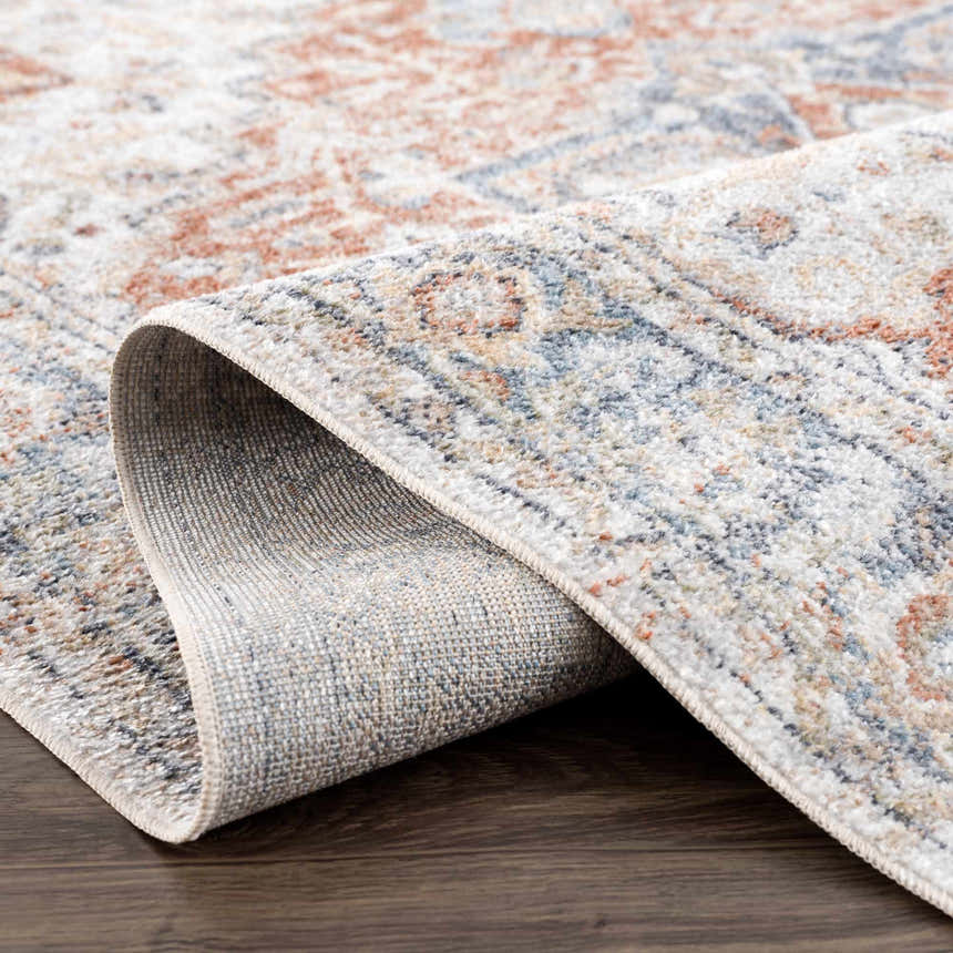 Close-up of the Akram Gray & Orange Washable Area Rug showing its traditional vintage pattern and soft polyester texture. Fold