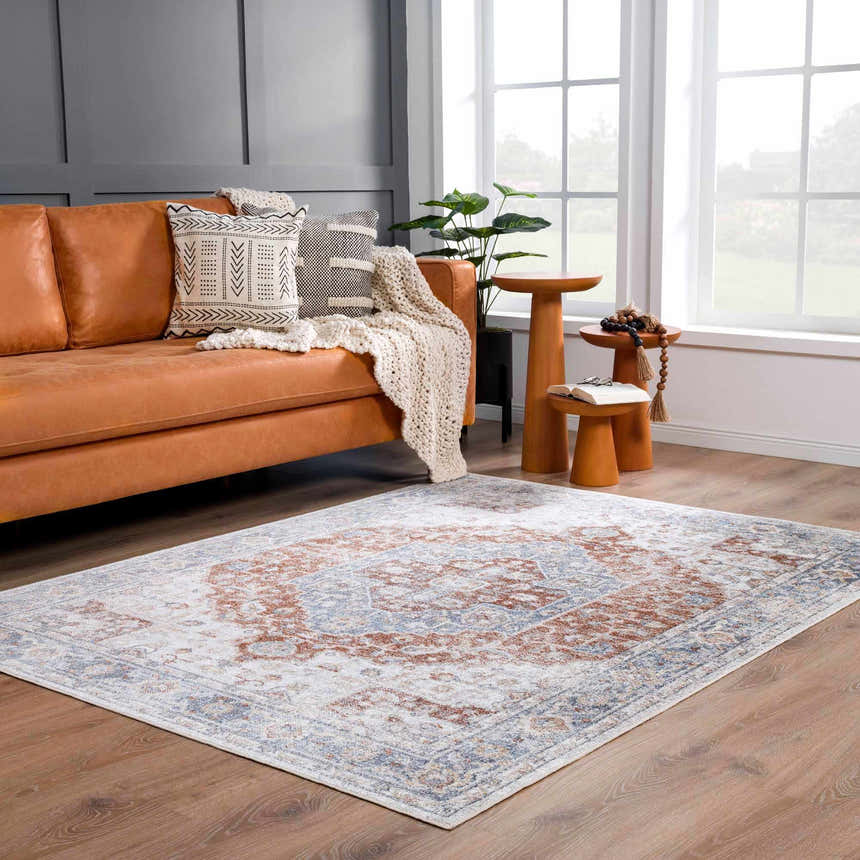 Living room scene with Akram Gray & Orange Washable Area Rug, leather sofa, wood stools, and natural light. Roomscene-Rectangle