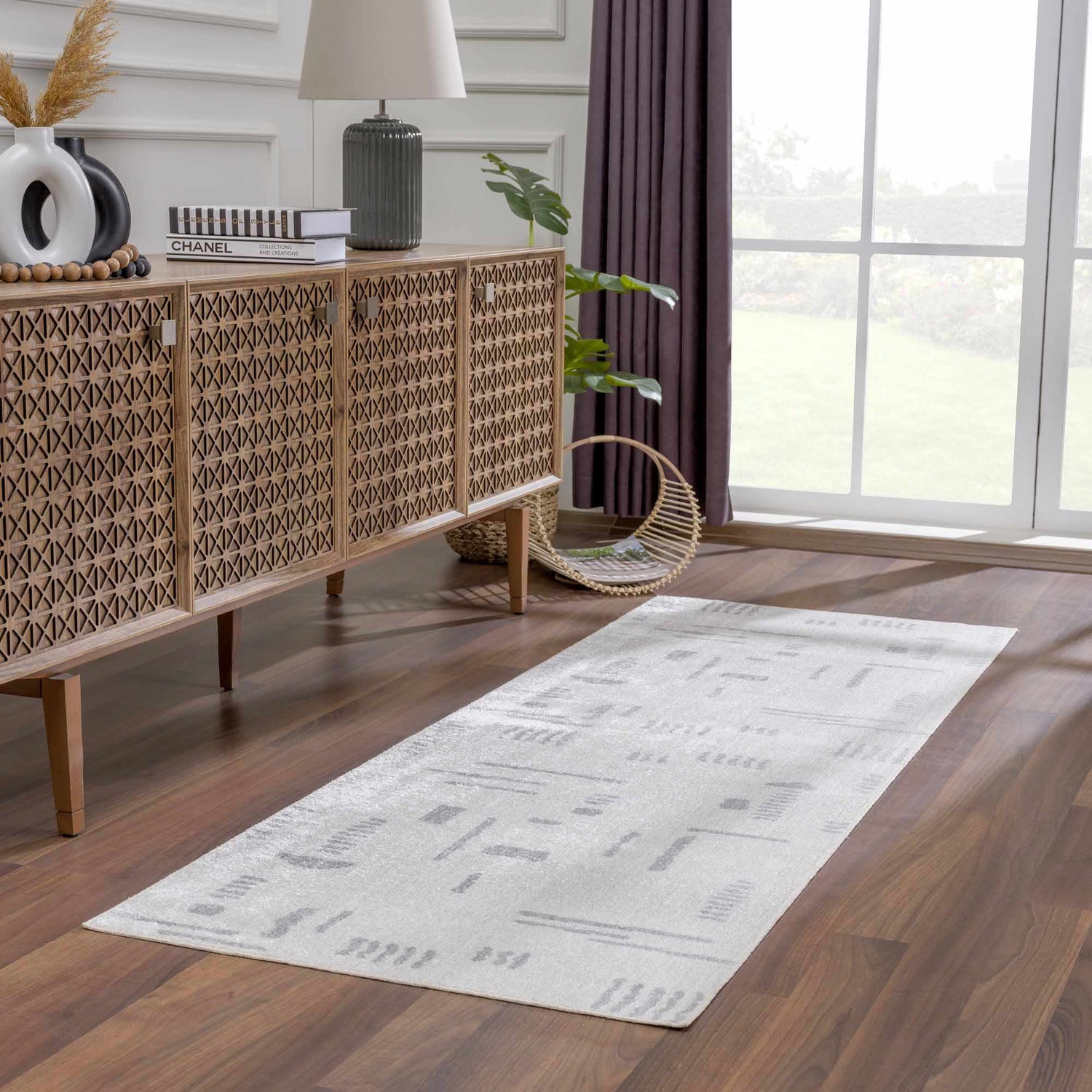 Living room scene with Eitan Modern Washable Off-White Rug, wood cabinet, lamp, and dark wood floors. Roomscene-Runner