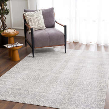 Living room scene with a gray chair on a Gravelbourg Washable Boho Rug in gray and light gray. Roomscene-Rectangle
