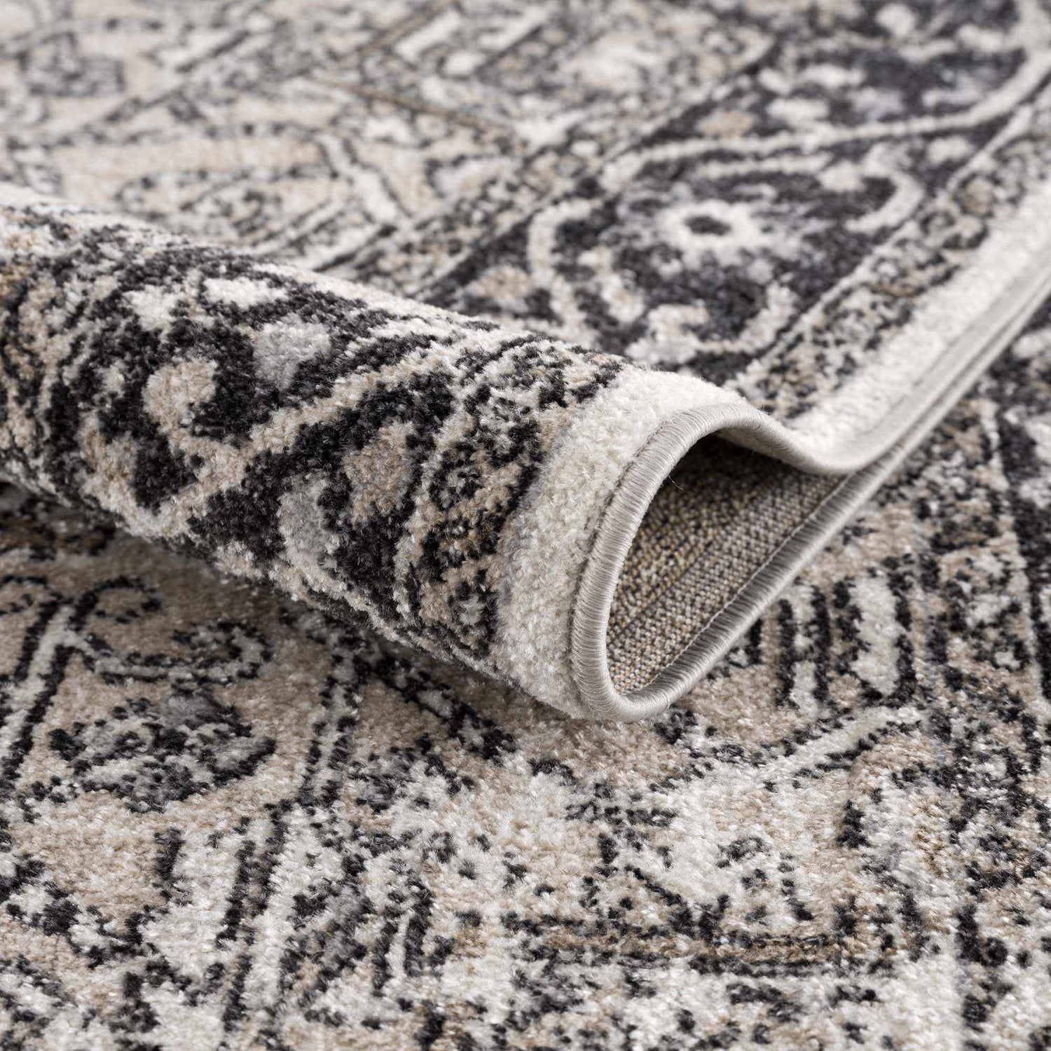 Close-up of the Cabacungan Washable Area Rug, showcasing its black, gray, and beige vintage-style pattern and soft texture. Fold