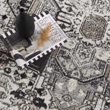 Close-up of the Cabacungan Washable Area Rug. Black, gray, light beige, and taupe vintage-style rug with a geometric pattern. Styleshot
