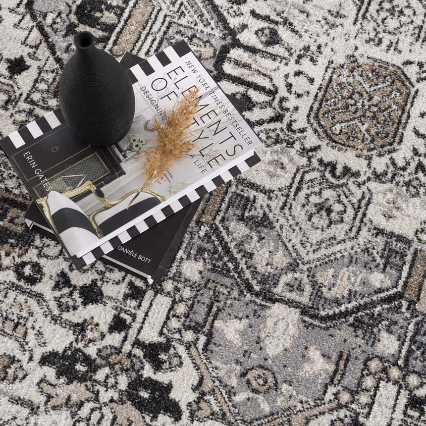 Close-up of the Cabacungan Washable Area Rug. Black, gray, light beige, and taupe vintage-style rug with a geometric pattern. Styleshot
