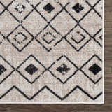 Close-up of the Joppatowne Washable Area Rug. Black geometric pattern on cream and light beige polyester. Machine woven texture. Swatch