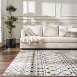 Living room scene with a cream sofa and the Joppatowne Washable Area Rug in black and cream with geometric pattern. Roomscene-Rectangle