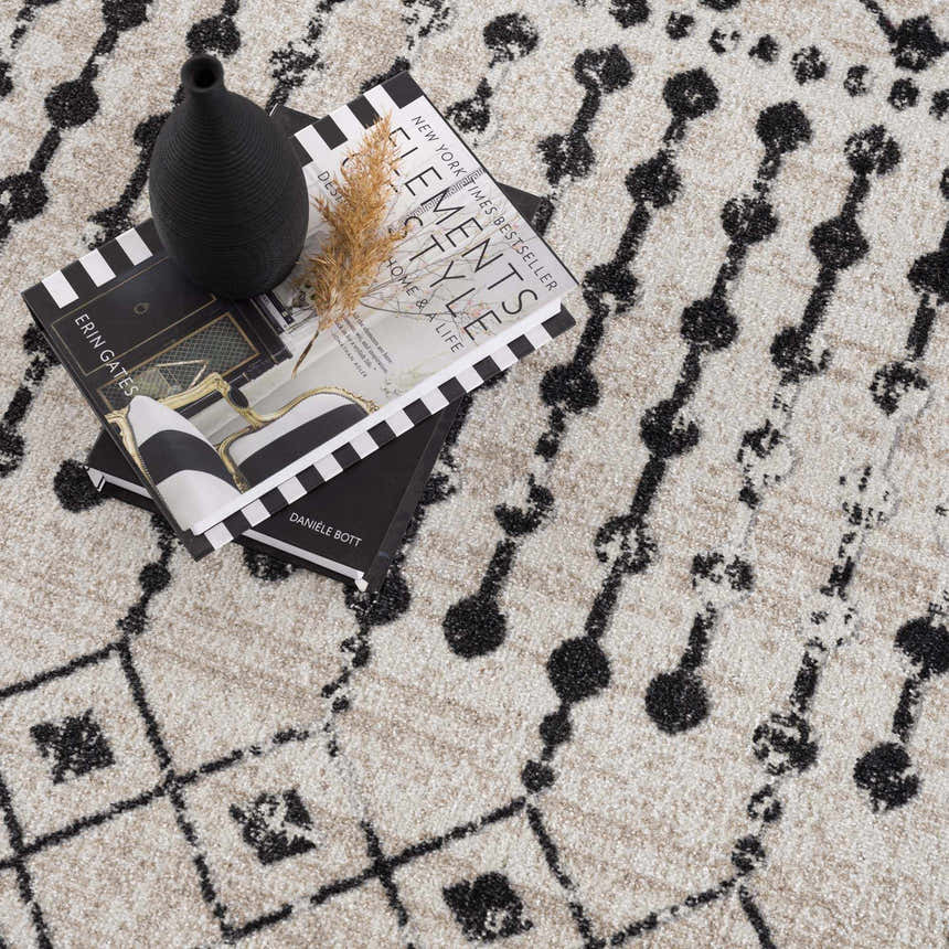 Close-up of the Joppatowne Washable Area Rug featuring a black geometric pattern on a cream and light beige background. Styleshot