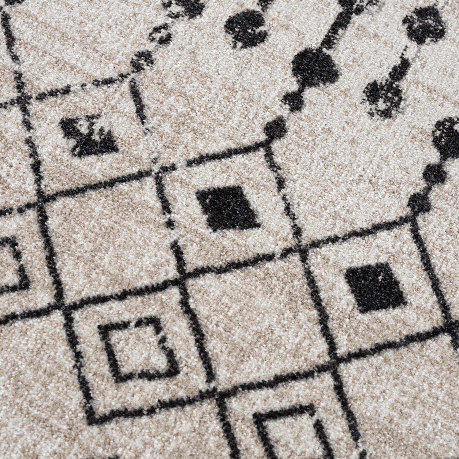 Close up of the Joppatowne Washable Area Rug showing its black geometric pattern on a cream and light beige background. Texture