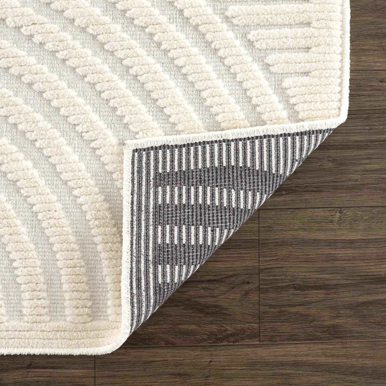 Close-up of the Deron White Washable 3D Rug showing its geometric pattern, off-white color, and underside. Fold