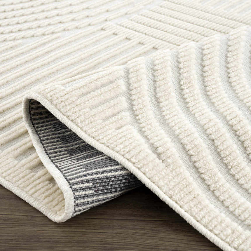 Close-up of the Deron White Washable 3D Rug showing its off-white color, geometric pattern, and textured, machine-woven construction. Fold