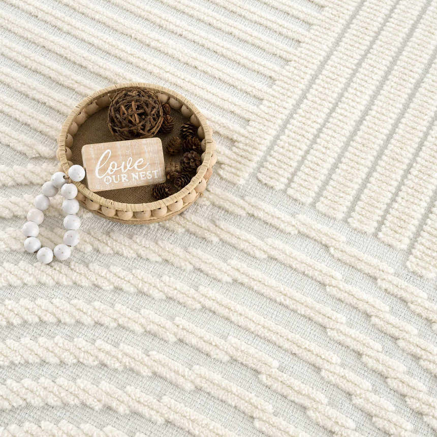 Close-up of the Deron White Washable 3D Rug featuring a geometric pattern and textured, off-white and gray color palette. Styleshot