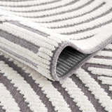 Close-up of the Deron Gray Rainbow Washable Rug showing gray and white geometric stripes and soft, textured pile. Fold