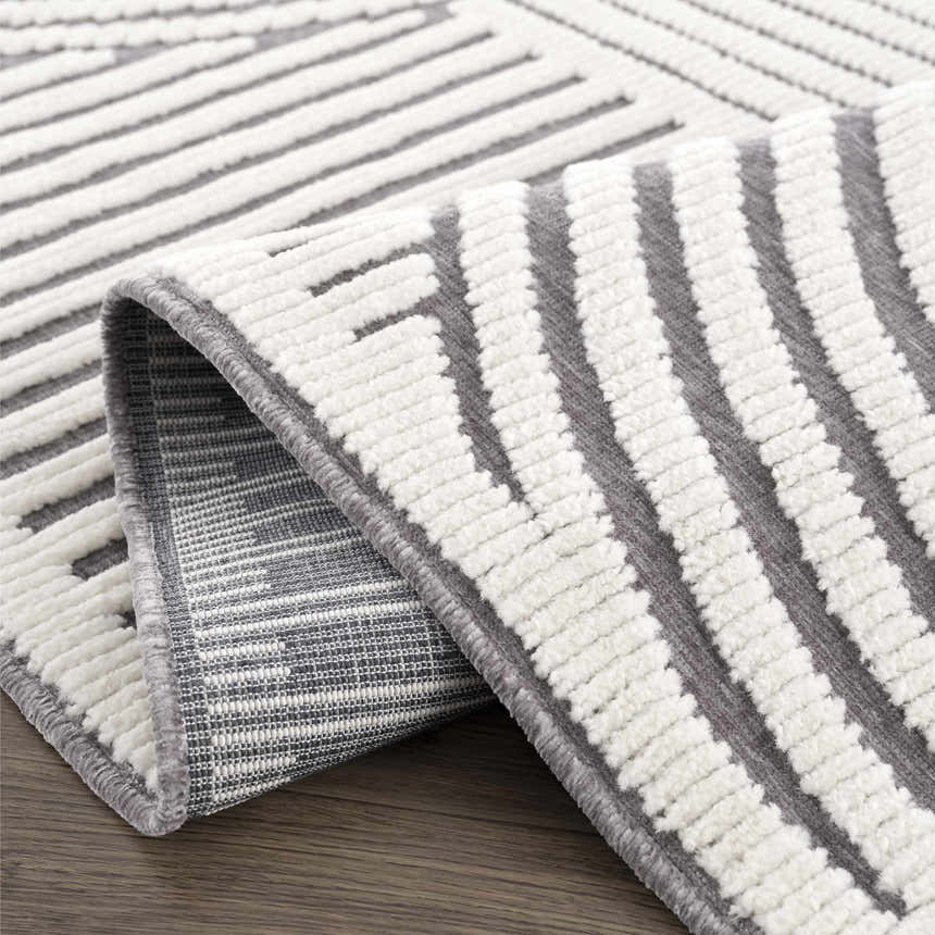Close-up of the Deron Gray Rainbow Washable Rug featuring a geometric pattern in gray and white with a soft, textured pile. Fold