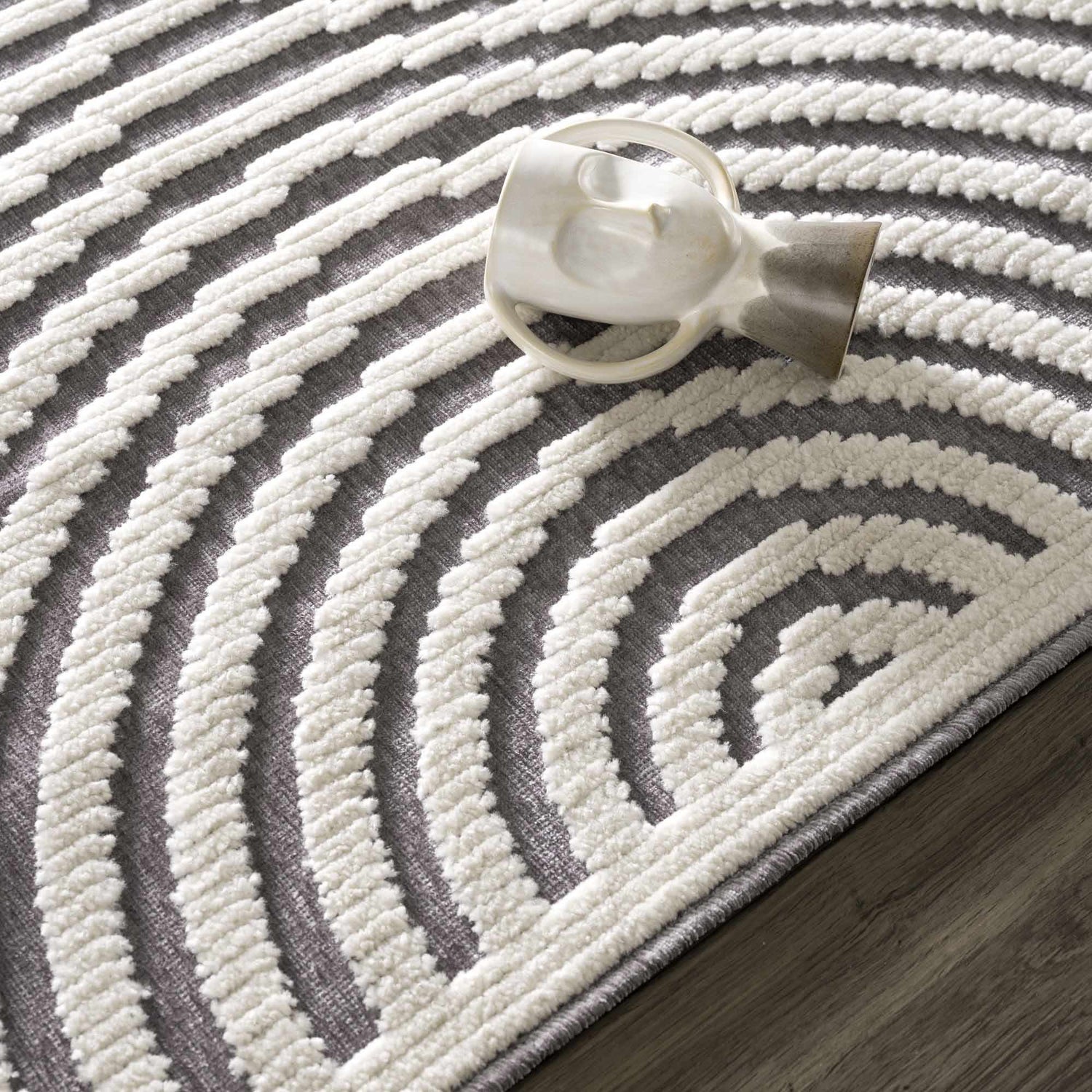 Close up of the Deron Gray Rainbow Washable Rug, featuring a geometric pattern in gray and white with a textured, machine-woven design. Styleshot