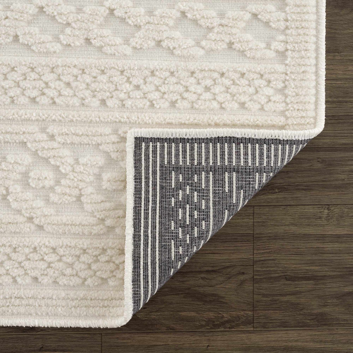 Close-up of the Fadey White 3D Washable Rug showing geometric texture, soft pile, and durable backing on wood floor. Fold