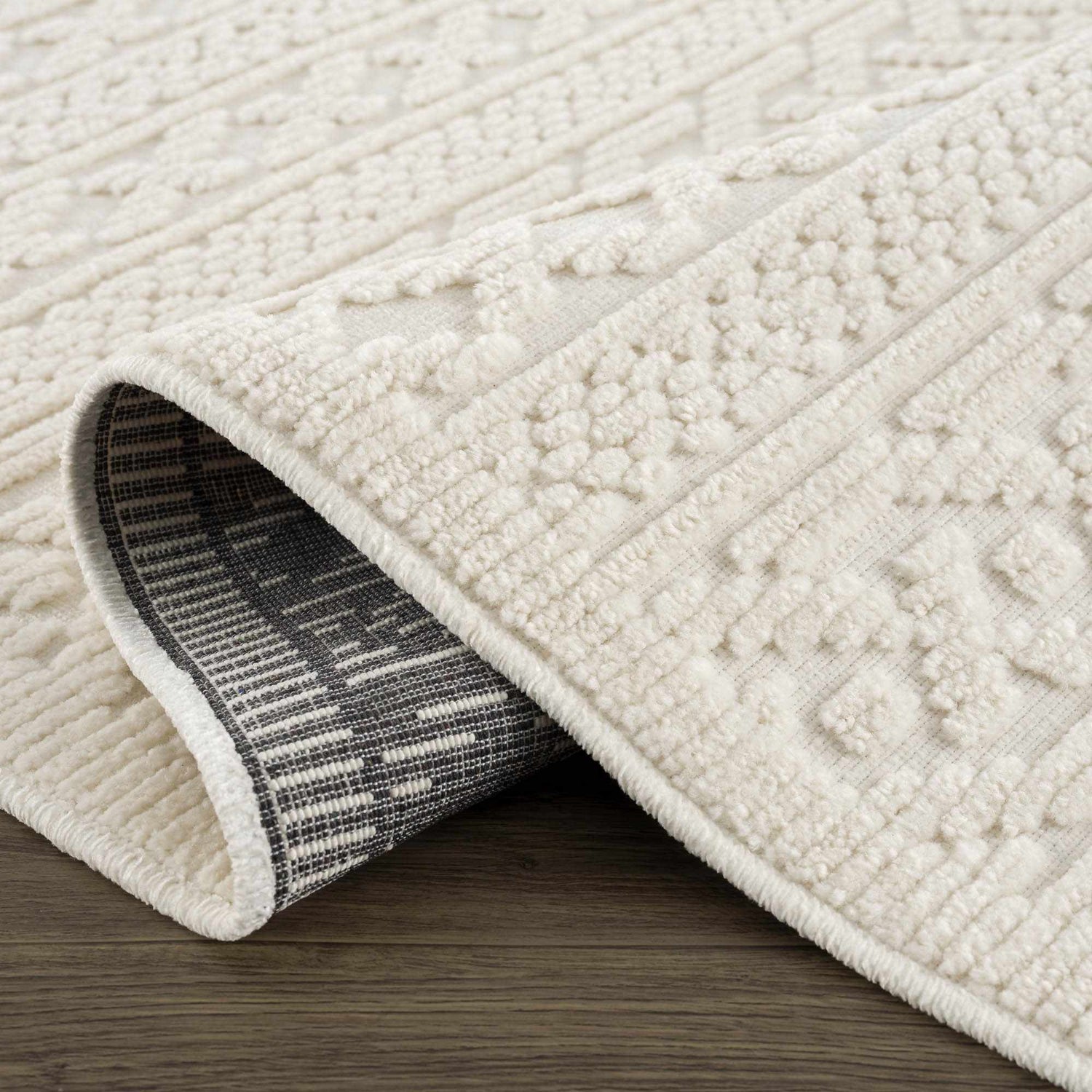 Close-up of the Fadey White 3D Washable Rug showing its geometric pattern and soft, textured pile on a wood floor. Fold