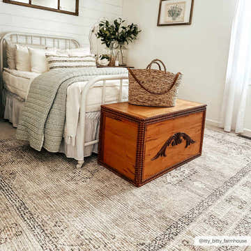 Farmhouse bedroom scene with a Lila Medallion Off-White Area Rug, wooden chest, metal bed frame, and neutral decor. Roomscene-Rectangle