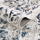 Close-up of the Duena Area Rug showing its blue and light gray traditional pattern and machine woven construction. Fold
