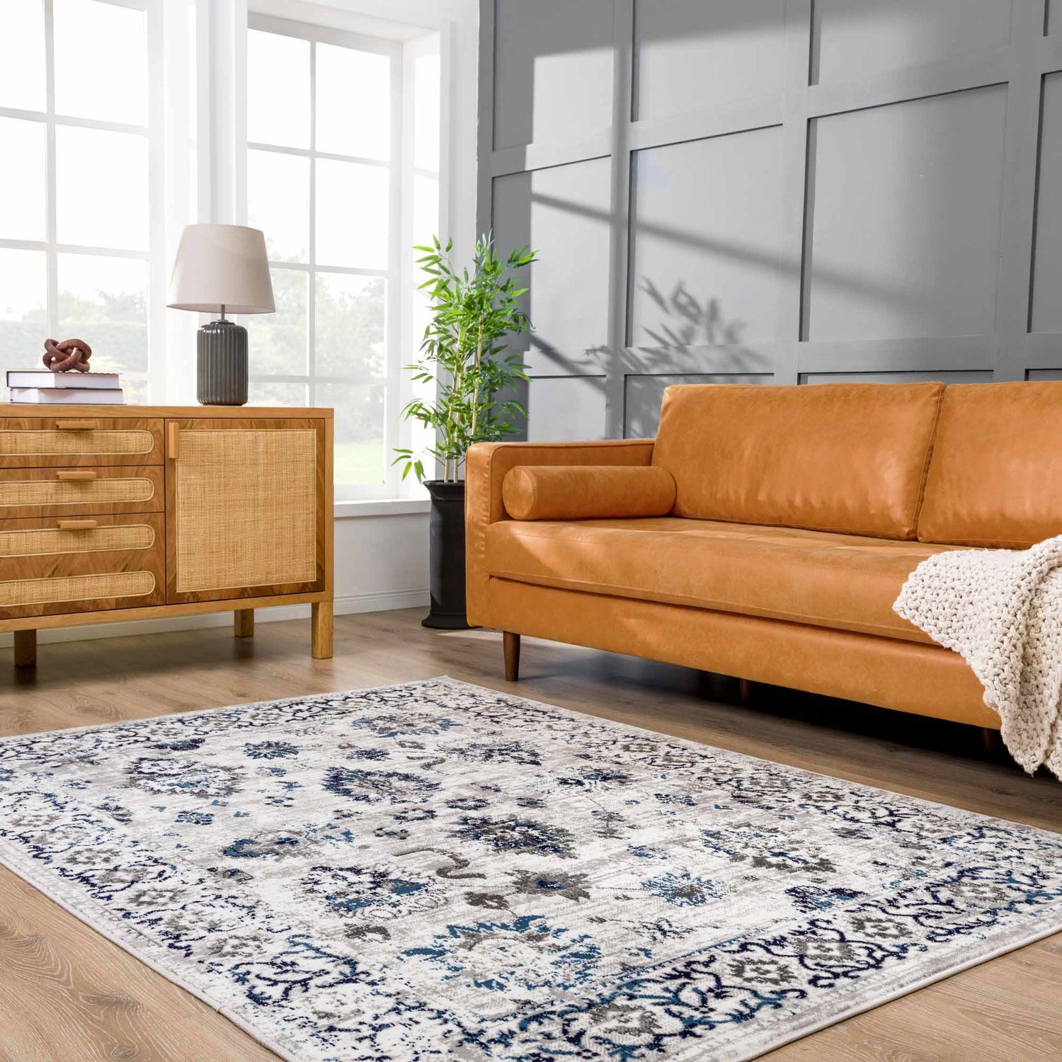 Living room scene with a blue and light gray Duena Area Rug, tan leather sofa, and wood cabinet. Roomscene-Rectangle