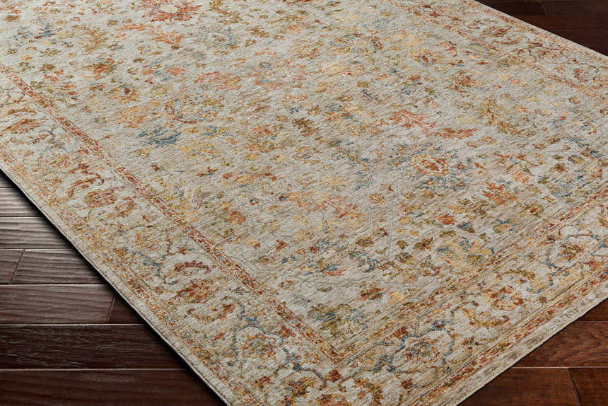 Close-up of the Asabi Tan Textured Rug. Features a traditional floral pattern in brick red, sage, navy, and mustard on a tan background. Corner