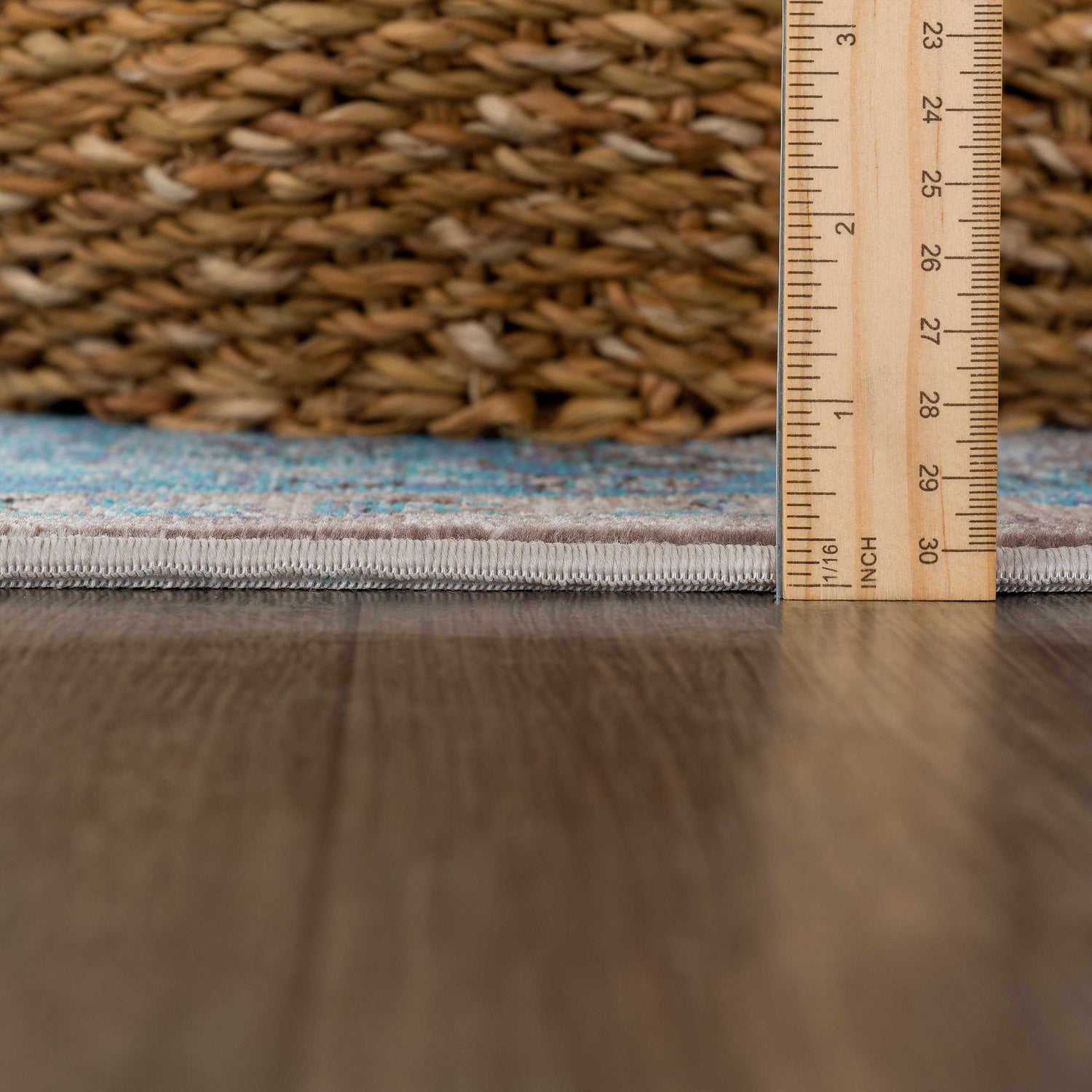 Close-up of the Mardina Turquoise Area Rug showing the rug's pile height with a ruler and a woven basket in the background. Pile