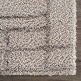 Close-up of the plush Andia Gray Area Rug showing its silver tones, shag texture, and geometric pattern. Swatch