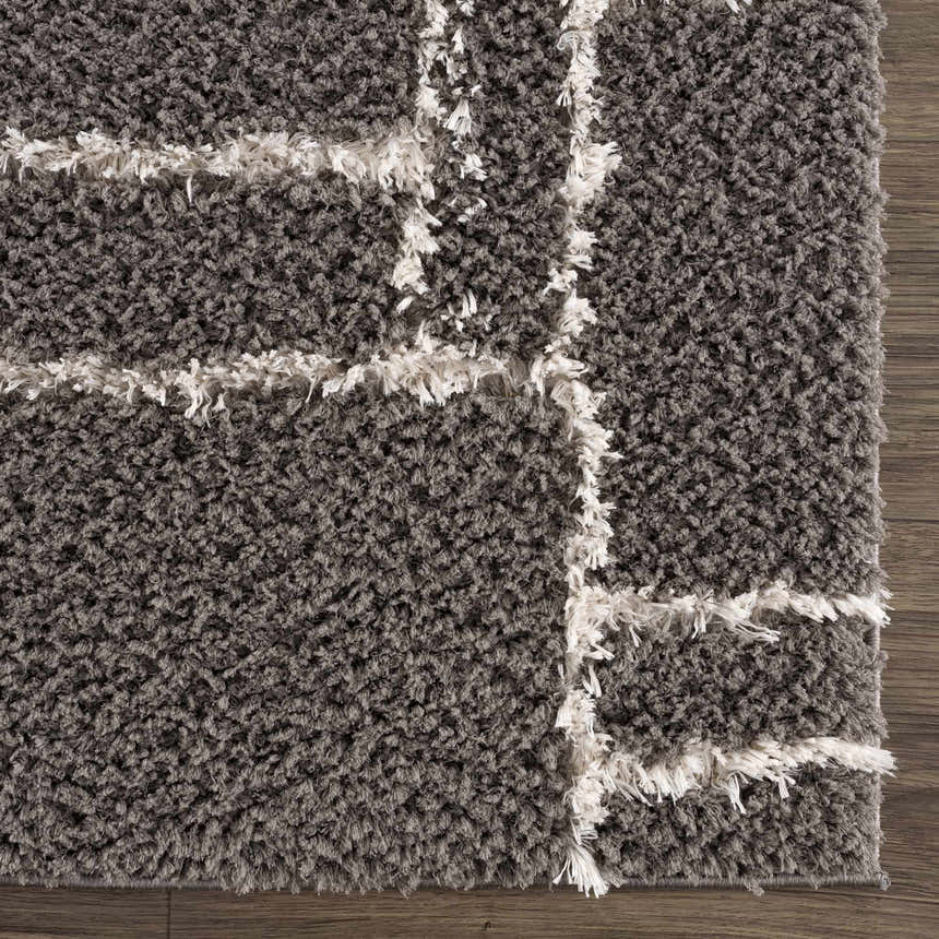 Close up of the Andia Charcoal Area Rug showing the gray shag texture and white geometric pattern. Swatch
