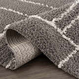 Close-up of the Andia Charcoal Area Rug showing its shag texture and geometric white line design. Fold