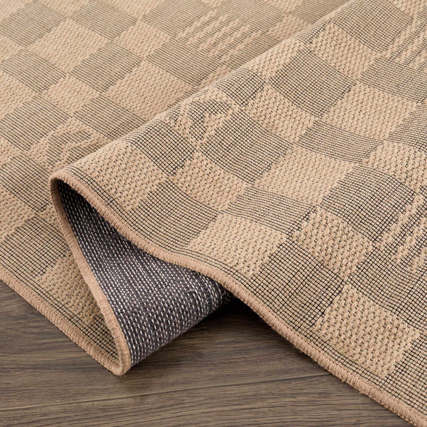 Close-up of the Nairi Checkered Washable Jute Rug. Beige and black checkered pattern with jute texture. Machine woven rug. Fold