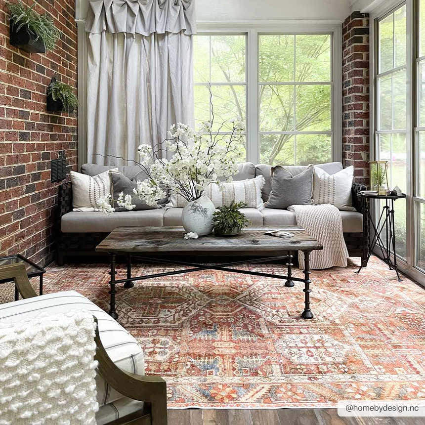 Sunroom with brick walls, sofa, and the brick red Mantalongon Washable Area Rug in a bohemian style. Roomscene-Rectangle