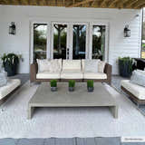 Cream Maribyrnong 3D Outdoor Area Rug in a modern farmhouse patio scene with wicker sofa and concrete coffee table. Roomscene-Rectangle