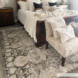 Bedroom scene with a beige and black Minoa Area Rug, dark wood bed, and neutral decor. Roomscene-Rectangle