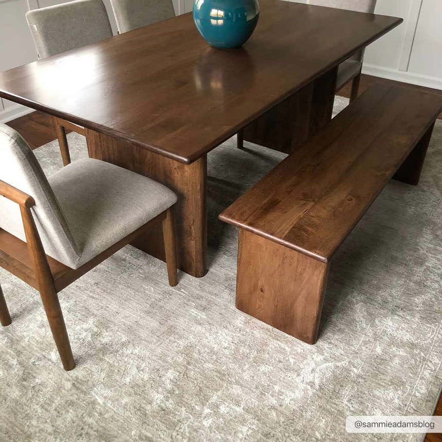 Dining room scene with wood table, bench, and gray chairs on a Monto Luxe Rug in cream and gray. Styleshot