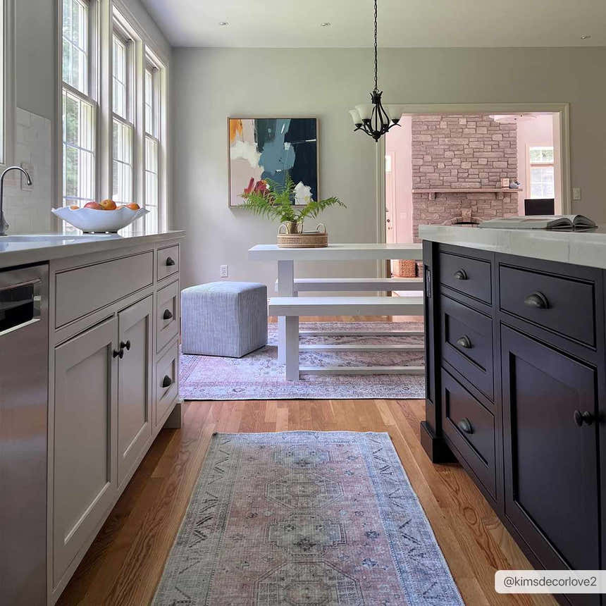 Farmhouse kitchen with a Morcott Peach Washable Area Rug, white table, and black kitchen island on wood floors. Roomscene-Runner