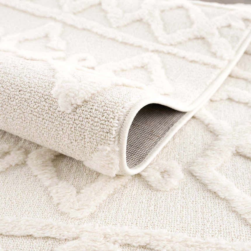Close-up of the Gyundyukoru Area Rug showing the bone and cream geometric pattern and machine woven texture. Fold