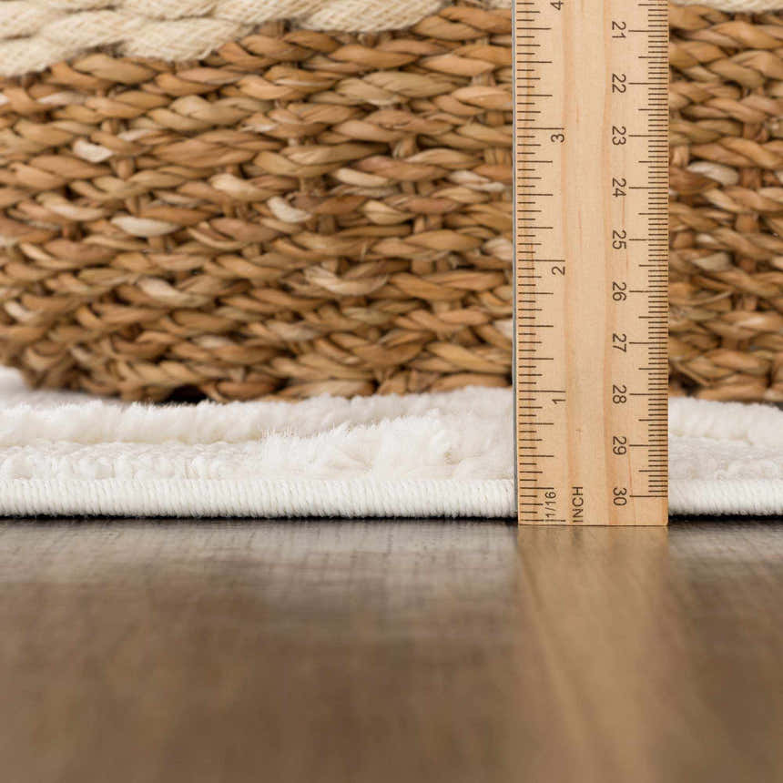 Close-up of the plush, bone-colored Gyundyukoru Area Rug showing its texture and pile height with a ruler for scale. Pile