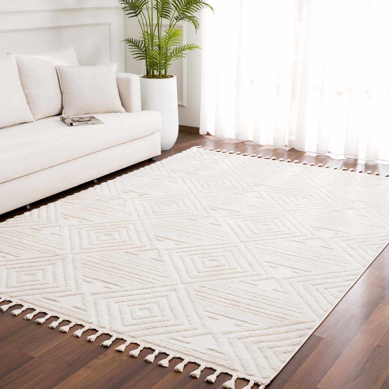 Living room with white sofa and Manyas 3D Bone Area Rug. The rug has a geometric pattern and tassels. Roomscene-Rectangle
