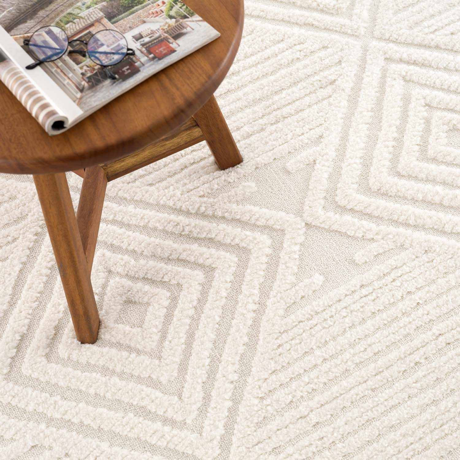 Close-up of the bone-colored Manyas 3D area rug, showcasing its geometric pattern and textured, plush pile. Styleshot