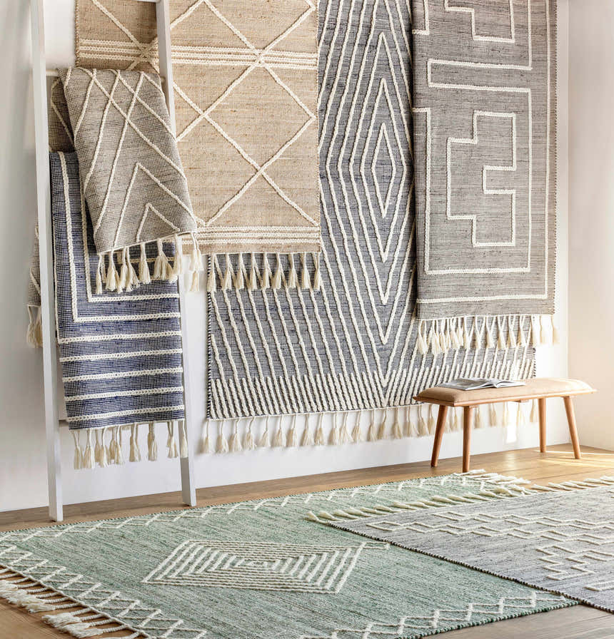 Rug display with Bohemian, Farmhouse style Tamayong Tasseled Jute&Wool Rugs in black, cream, and ink blue. Hand woven texture and tassels. Styleshot