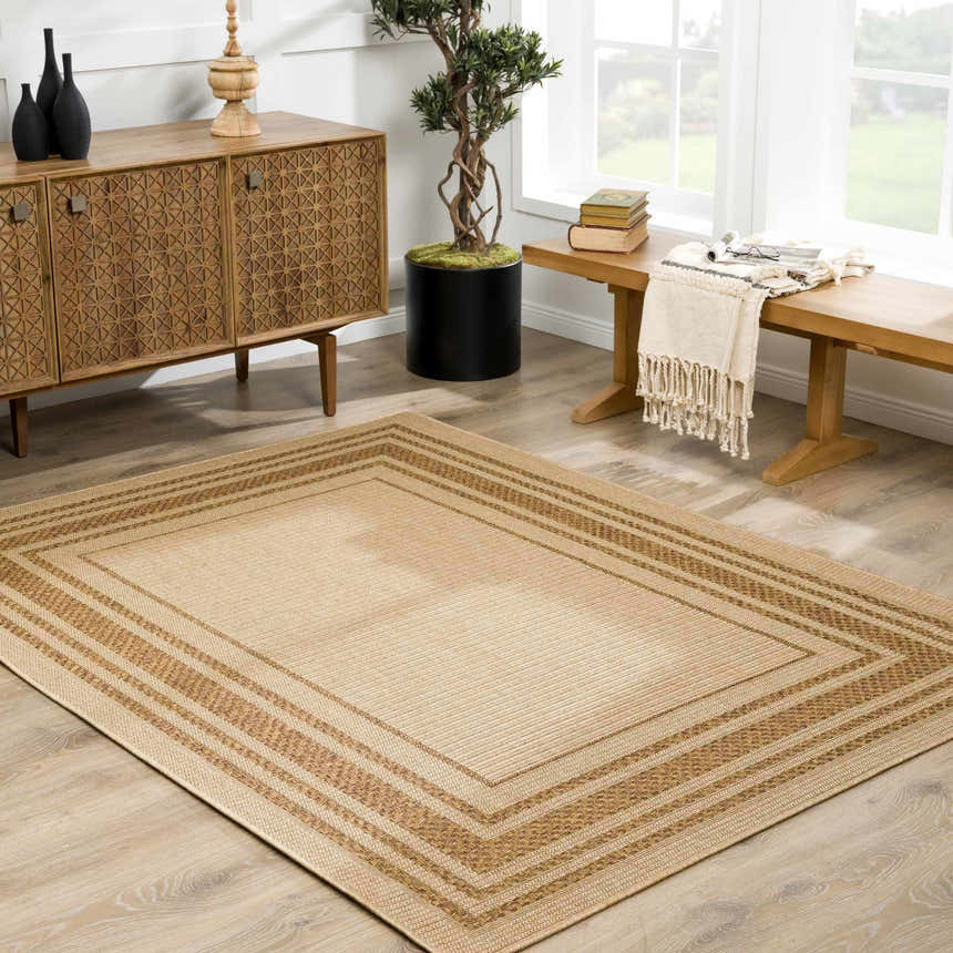 Living room scene with a camel Isoko Bordered Faux Jute Rug, wood cabinet, bench, and plant creating a warm, inviting space. Roomscene-Rectangle