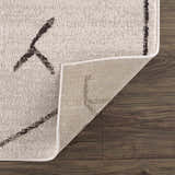 Close-up of Azzan Cream & Charcoal Area Rug showing the cream color, charcoal geometric pattern, and rug backing. Fold