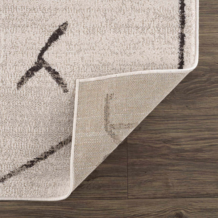 Close-up of Azzan Cream & Charcoal Area Rug showing the cream color, charcoal geometric pattern, and rug backing. Fold