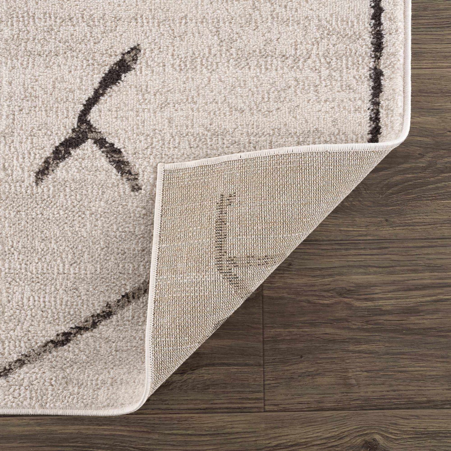 Close-up of Azzan Cream & Charcoal Area Rug showing the cream color, charcoal geometric pattern, and rug backing. Fold
